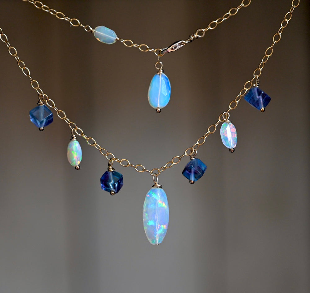 Necklace with blue and gold beads on a gradient background. Ethiopian opal gemstone necklace with violet fluorite stones 14K gold filled jewelry OpalOra.