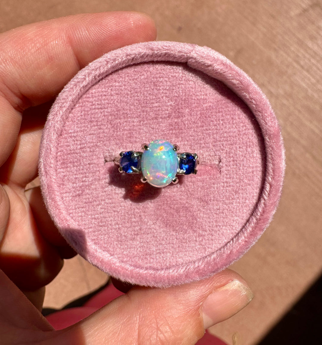 Custom opal ring with blue sapphires in 14K white gold, front view showing opal center stone