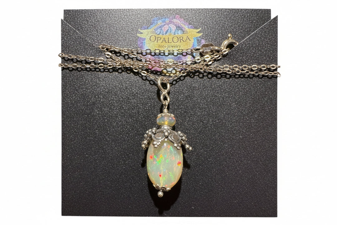 Opal necklace on a black card with 'Opalora' branding. OpalOra angelic talisman rainbow opal pendant sterling silver handcrafted charm necklace with vibrant color play