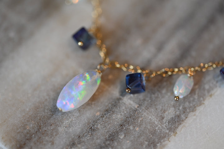 Necklace with opal and fluorite stones on a marble surface. Statement necklace with Ethiopian white opal and violet fluorite gemstones handcrafted by OpalOra jewelry.