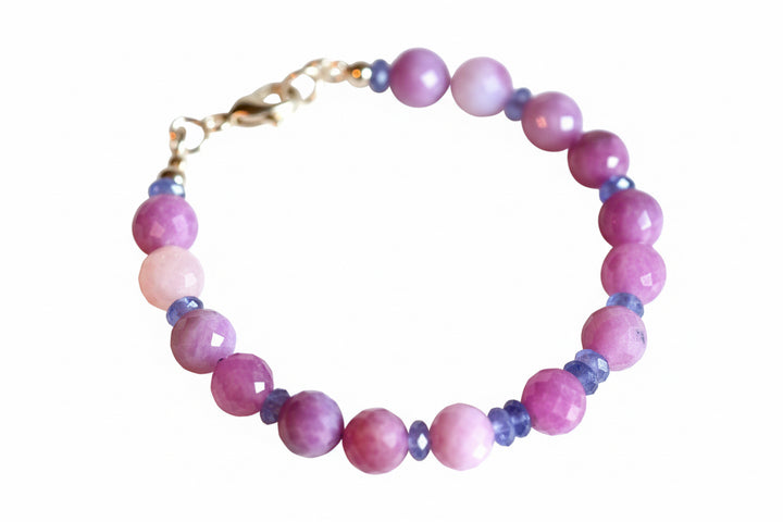 A 14-karat gold bracelet featuring genuine pink natural round ruby beads and stunning rondell-shaped Tanzanite beads with a secure lobster clasp.