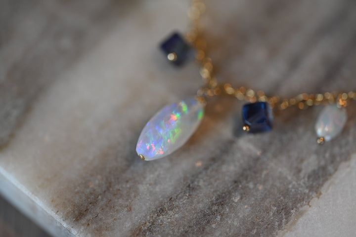 Close-up of a necklace with opal and blue stone pendants on a marble surface. Gift necklace Ethiopian opal and purple fluorite beaded gemstone jewelry gold filled chain OpalOra.